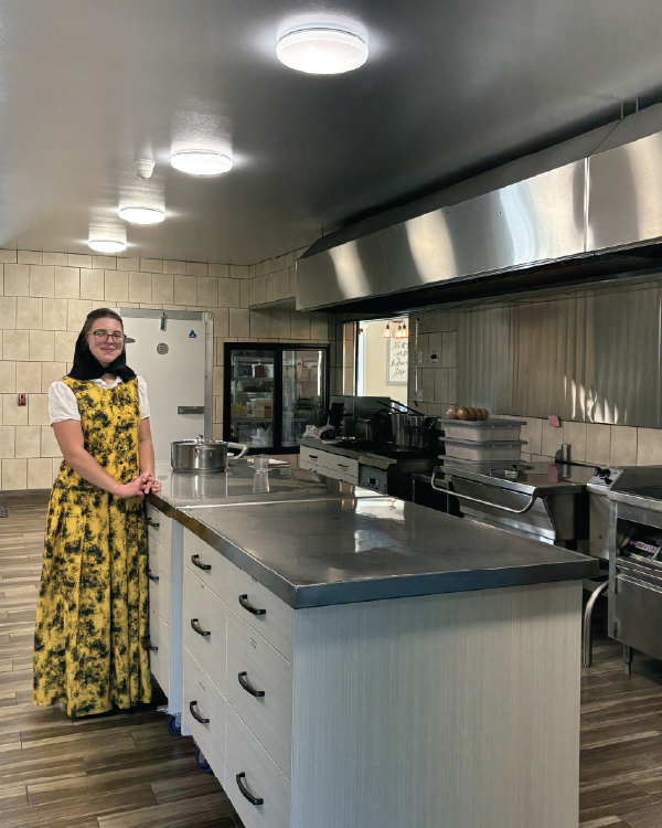 Member of Deerboine colony standing in the kitchen area of their facility with their new overhead LED fixtures.