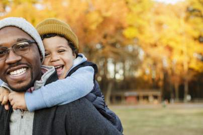 Un père portant son fils sur le dos dans un parc