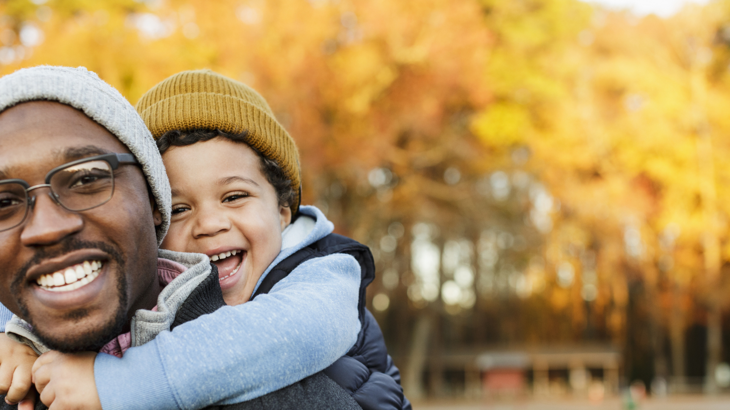 Father carrying son piggyback in park