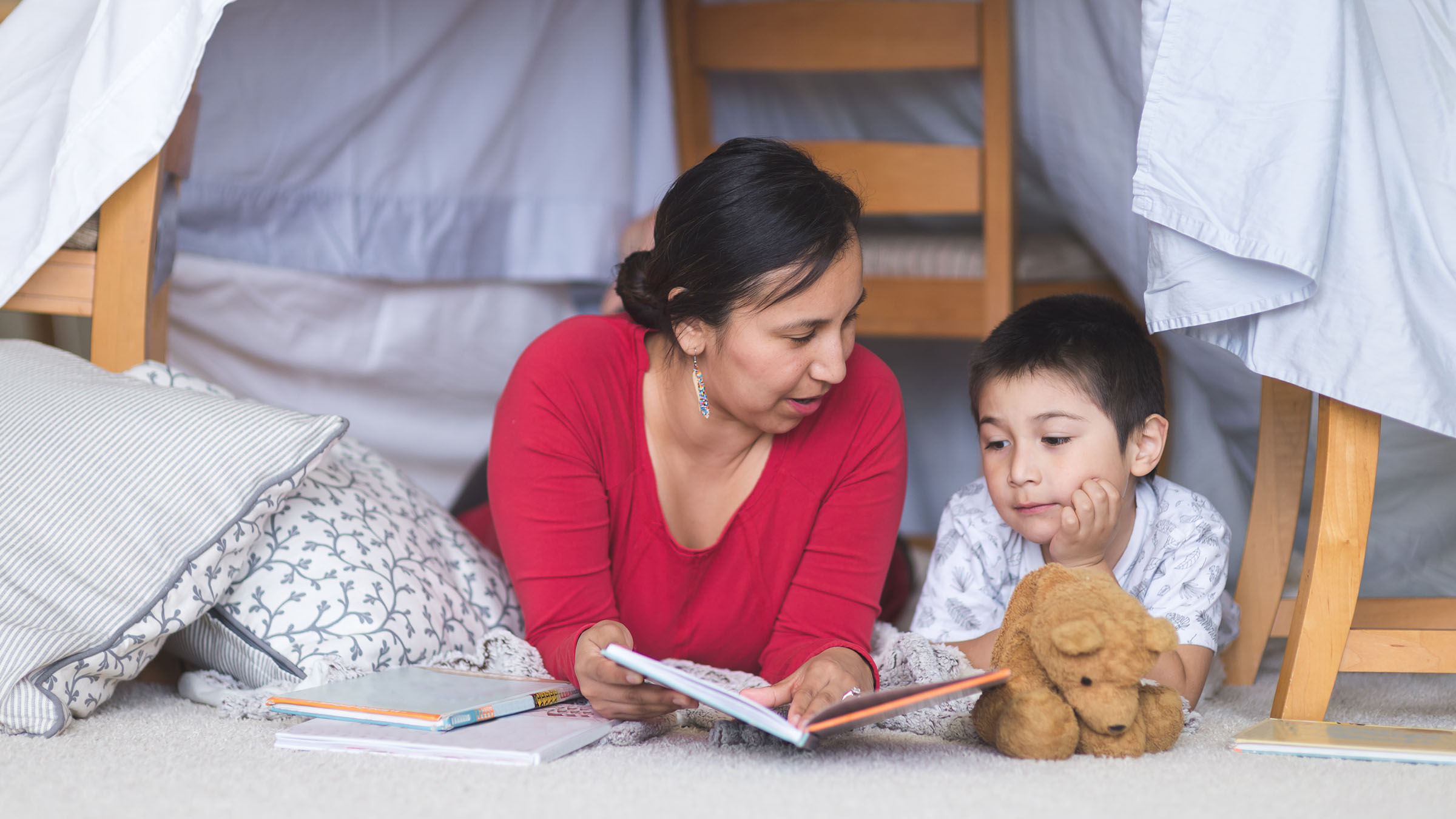 Mère qui lit à son enfant sous des couvertures